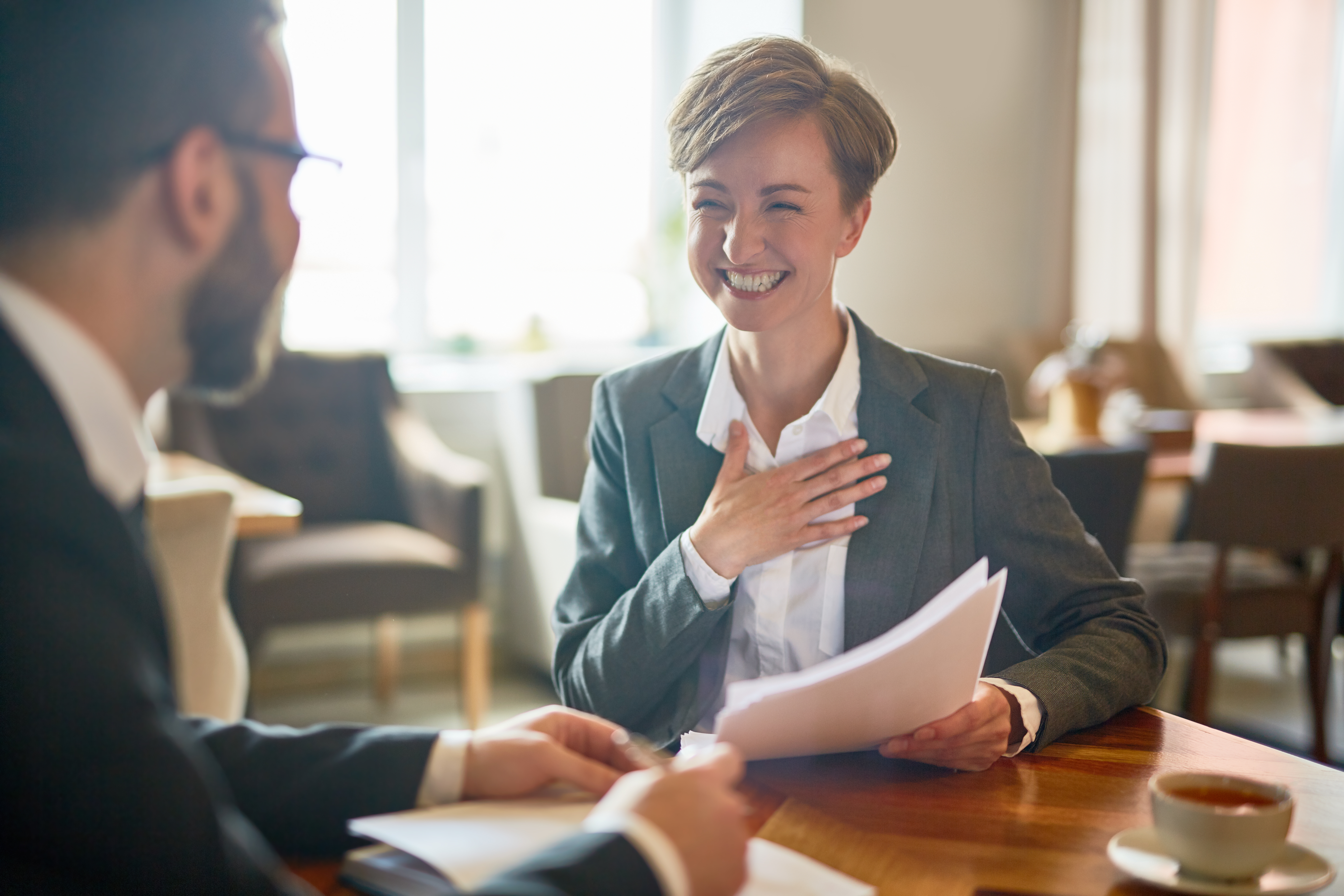Laughing businesswoman with papers talking to her colleague during meeting in cafe, Laughing businesswoman with papers talking to her colleague during meeting in cafe